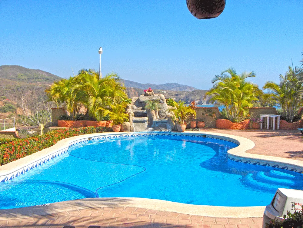 Piscina de forma libre con cascada de roca y vista al océano en el Hotel Yuritzi
