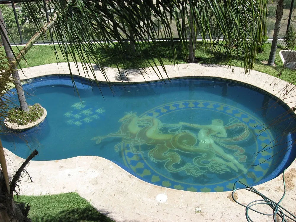 Piscina residencial de forma libre con un mural de mosaico veneciano en el fondo