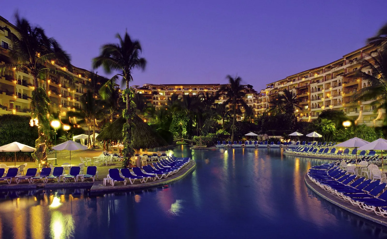 Albercas iluminadas al anochecer en el desarrollo Velas Vallarta, Puerto Vallarta